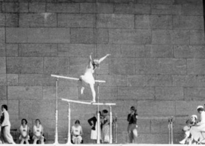 Edna Gross performing the compulsory exercise as member of the team sit at the side